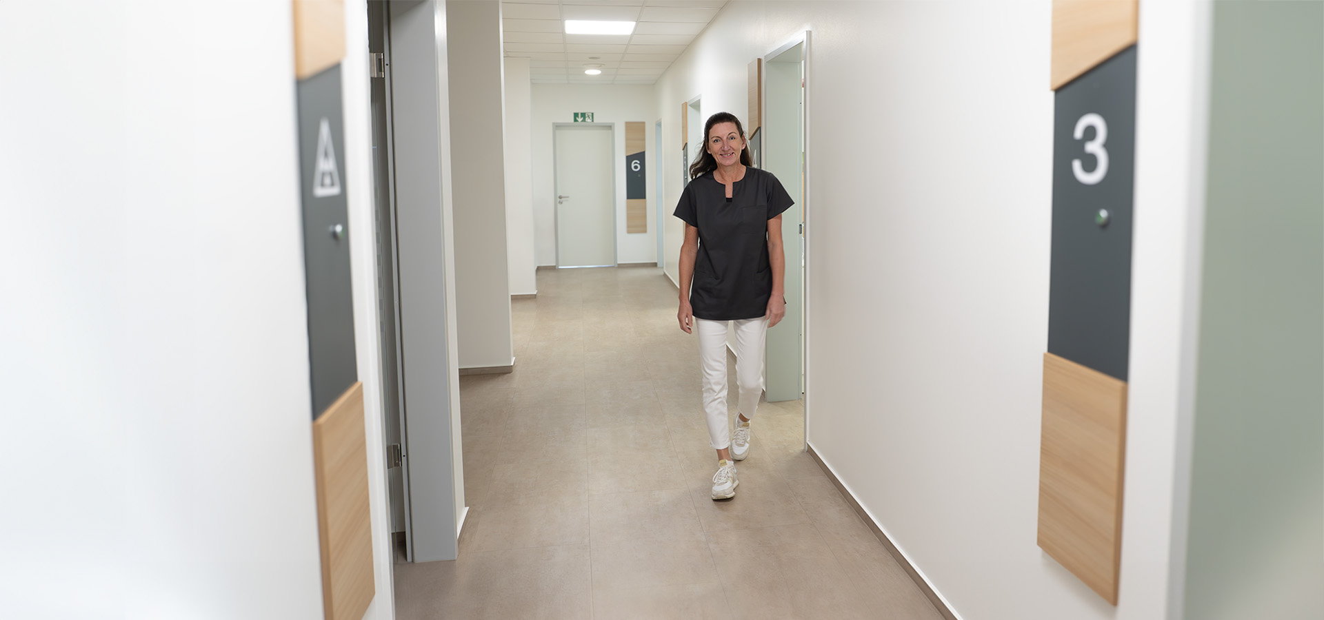 Dr. Sabine Küpers geht lächelnd durch den Flur ihrer Zahnarztpraxis.